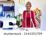afro american woman with turban over head and silver ethnic colorful jewelry in tailor workshop