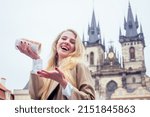 woman with an appetite eats a traditional Czech sweet Trdelnik in street Prague s Old Town Square