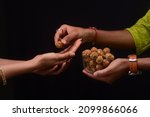 Small photo of Hand giving a sesame seed balls or Til Gul Ladoo, Happy Makar Sankranti