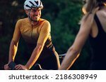 Happy couple riding road bicycles outside. Healthy lifestyle and fun concept. Athletic couple riding while wearing sports clothing, protective helmets and sunglasses. Focus on a smiling man.