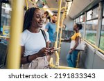 Young african american woman reading a text message on her smartphone while riding a bus. Black woman catching up on social media while in a bus during her morning commute. Copy space.