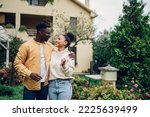 Portrait of a diverse couple holding keys and standing outside their new home on a moving day and looking at each other. Multiracial people outside their new house. Copy space. Investing in property.