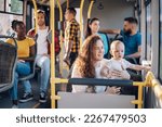 Young caring mother sitting with son in a bus while riding in a city. Boy is sitting in her lap and looking trough a window. Close up of plus size mom holding her child in public transportation.