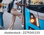 Cropped shot of an african american woman entering the bus while standing at the station.Black unrecognized female get in the public transportation while going to work or school. Copy space.