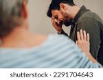 Small photo of Portrait of a sad young man on group therapy meeting discussing addiction and mental health problems. Multiracial people talking about their mental health issues. Senior woman comforting him.