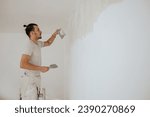 Small photo of A constructor is standing on ladders and using building tools and materials for plasterwork and skim coating walls. A worker is using trowel and spatula for plastering walls and renovating. Copy space