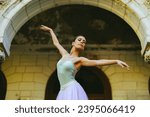 Portrait of a graceful classic ballerina woman with hair tied in a bun dancing while wearing white dress and enjoying in every movement. Grace and motion concept. Copy space.