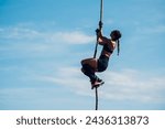 Small photo of Side view of a fit woman athlete partake in one of the events of an obstacle course race while climbing a rope. Female working out outside. Sport competition and OCR race. Copy space.