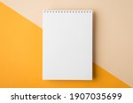 Minimal style note pad. Above overhead close up flat lay photo of clear spiral notepad with copy place for design isolated half yellow and beige backdrop desktop