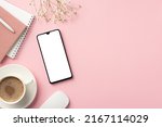 Business concept. Top view photo of workspace smartphone planners pen cup of coffee on saucer computer mouse and white gypsophila flowers on isolated pastel pink background with blank space
