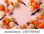 Small photo of Sleek Halloween decor display. Top view capturing thematic items: small orange and golden pumpkins, bugs, ghastly spiders, spiderweb, bats on pastel pink base. Empty space for greetings or promos