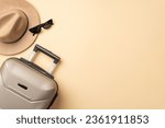 Small photo of Autumn travel dreams. An aerial shot showcasing a gray suitcase along with a snug felt hat, and sunglasses laid out on beige isolated background, ideal for your promotional or textual needs