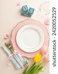 Small photo of Feminine-themed dining table design. Overhead vertical shot of sophisticated plate, linen napkin, flatware, claret glass, pretty tulips, perpetual calendar on soft beige canvas, with area for advert