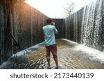 Small photo of Man take a photo of flowing water like a small waterfall curtain. Water overflowing the mortar weir during the rainy season with tree and sunlight background at Pang Sawan Weir, Uthai Thani, Thailand.