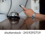 Small photo of HOTEL RECEPTIONIST WITH CELL PHONE TAKING RESERVATIONS AND CLOSE-UP HOTEL RINGER