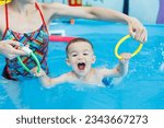 Small photo of A 2-year-old boy learns to swim in a pool with a coach. Swimming lessons for children. Swimming school for children. Educational swimming courses for children