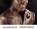 cropped shot of african american woman applying lipstick isolated on black