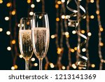 champagne in glasses and ribbons on garland light background, christmas concept
