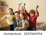 excited multiethnic kids playing musical instruments near happy teacher