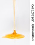 Small photo of trickle of fresh golden honey flowing on white