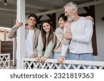 Small photo of parents day, middle aged parents hugging and looking away near teenage daughter and adult son on porch of summer house, family celebration, bonding, modern parenting, translation of tattoo: harm none