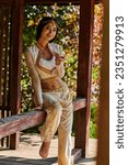 Small photo of summer park, brunette indian woman in vibrant traditional clothes smiling at camera in wooden alcove