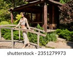 Small photo of happy indian woman in authentic clothes standing on wooden bridge near alcove in summer park