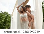 Small photo of beautiful couple, handsome man seducing woman while standing together near beach pavilion
