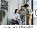 Small photo of group shot of diverse business people, disabled woman on wheelchair looking at laptop with coworkers