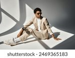 African American man in tan suit sitting on floor, wearing sunglasses.