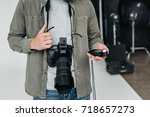cropped view of professional male photographer with digital photo camera and light meter in photo studio