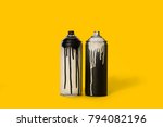close up view of black and white aerosol paint in cans isolated on yellow