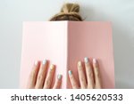 Stylish trendy color female manicure . Women’s hands keep pink note pad