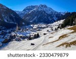 Scenic view of Mittelberg at ski region of snow covered Kleinwalsertal, Austria in winter with difficult conditions against blue sky