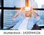 Man wearing virtual reality glasses sit on bean bag in living room.Lifestyle young man wearing virtual reality goggles experiencing future technology,interacting while playing. VR  fantasyland,