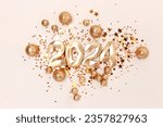 2024 gold colored numbers and glittering stars confetti on a beige background. New Year composition.
