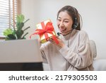 Asian women holding present box celebrating festive with family via video conference meeting online during social distance.