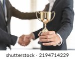 Small photo of The hands of an employee receiving a golden cup reward from the company manager represent his performance in his career job reward.