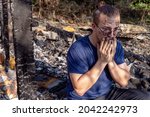 Small photo of Young man sits on the ruins of house destroyed with fire. Damaged window, walls and floor, burnt wooden frames. Tragic face, strong emotions, crying. Insurance or emergency concept, misadventure.