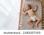 Small photo of Upper view copy space portrait of cute blond baby sleeping in bed on his back, feeling safe, watching sweet dreams, resting, growing, gaining strength, getting strong. Childcare concept. Nap time