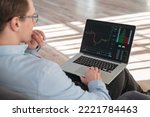 Close up shot of trade investor sitting with laptop on knees, analyzing candlestick diagram with stock market app, trying to predict actions of money flow, waiting for best moment to buy crypto