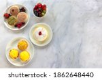 Small photo of A top down view of an assortment of Japanese cheese tarts and a jiggle soft Japanese sponge cheesecake on a white marble worksurface.