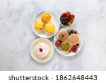 Small photo of A top down view of an assortment of Japanese cheese tarts and a jiggle soft Japanese sponge cheesecake on a white marble worksurface.