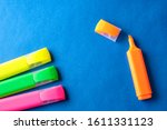Multi colored highlighters at blue background with copy space