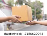 Postal service sending paper cardboard box to customer in front of a house outdoor. Shipping service arrival and send to customer address. 