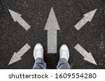 person standing on road with arrow markings pointing in different directions, decision making concept