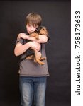Small photo of Happy boy portrait, boy and dog in love. Friends having fun whilst posing. Young little cute adorable kid and his puppy, obstreperous scamps. Poses, face expressions, ease, black background