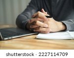 Close up of man clasped hands clenched together on table, businessman preparing for job interview, concentrating before important negotiations, thinking or making decision, business concept