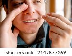 Man Cleaning teeth with a toothpick hiding mouth with hand. Male using Disposable Double-end Teeth Stick Floss Pick to clean teeth. Toothpick Dental Brush Oral Care concept