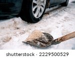 Small photo of Shovel with salt on snowy driveway to protect from slippery. Winter snow cleaning the road outside. Applying Rock Salt ( Gritting ) to an Icy road for safe car traffic. De icing Copy space
